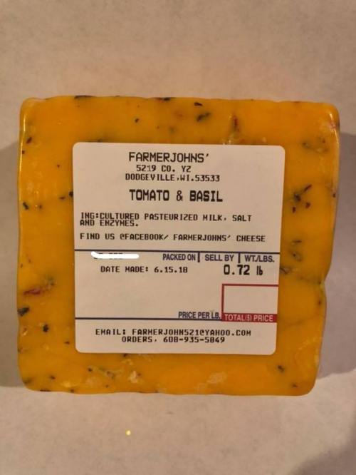 Label on a block of cheese, featuring "Tomato & Basil" with ingredients and packaging date. Weight: 0.72 lb.