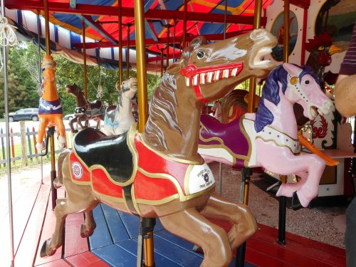A colorful carousel featuring ornate, painted horses in various poses, set against a vibrant striped canopy.
