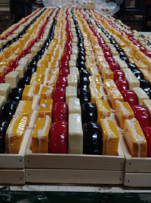 A colorful array of wrapped cheese blocks arranged in rows on a wooden table.