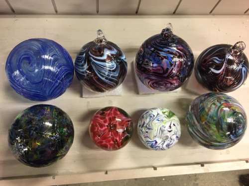 A collection of colorful glass orbs with swirling patterns, arranged in two rows on a white surface.