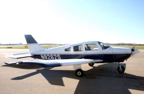 A small, single-engine aircraft parked on a runway under clear blue skies.
