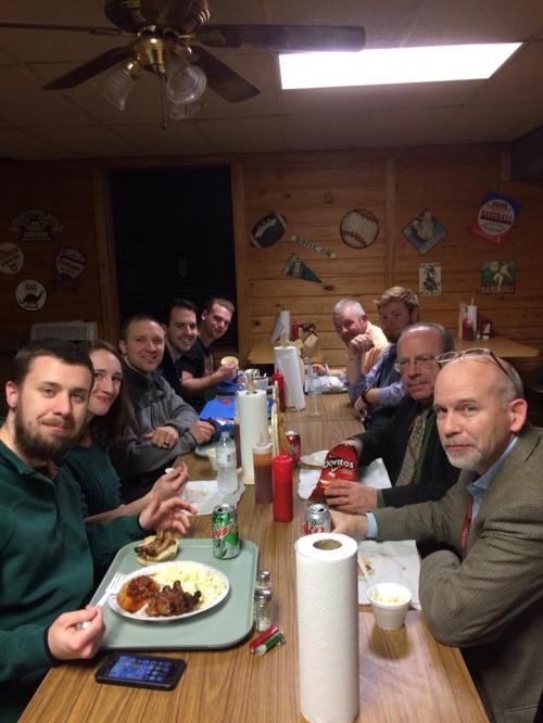 A group of people enjoying a meal together at a casual dining setting, with food and drinks on the table.