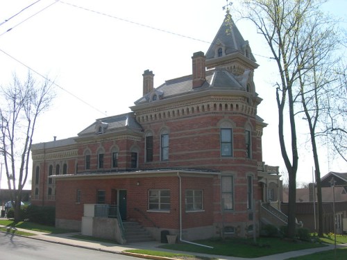 Historic brick building with a tower, intricate architectural details, and large windows, set against a clear blue sky.