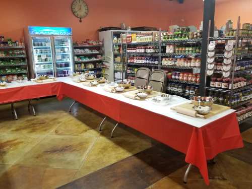 A brightly lit room with tables covered in red cloth, set for a meal, surrounded by shelves of food products.