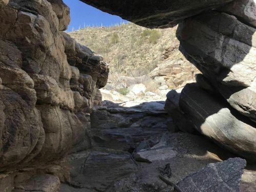 A rocky canyon with large boulders and a clear blue sky above, showcasing rugged natural formations.