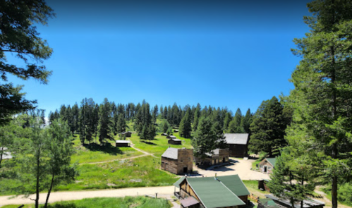A scenic view of a forested area with rustic buildings and a clear blue sky.