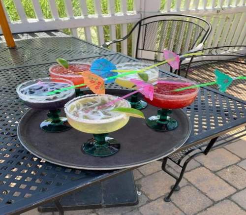 A tray of colorful cocktails with decorative umbrellas, set on a patio table.