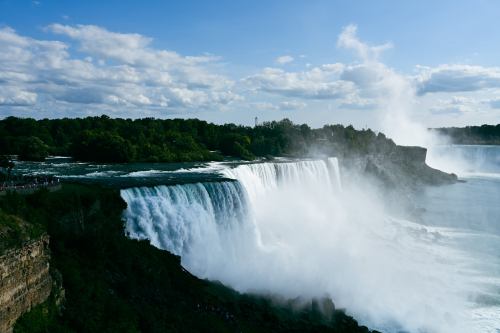 A stunning view of Niagara Falls, with cascading water and a blue sky dotted with clouds.