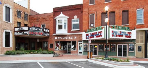 Historic theater district featuring the Brokaw Theatre and Strand Theatre, with brick buildings and a charming streetscape.