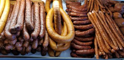 A variety of sausages displayed in a market, including long and coiled shapes in different shades of brown.