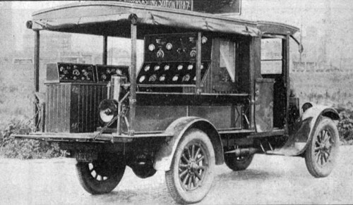 Vintage truck with a covered back, featuring numerous dials and gauges on the side.
