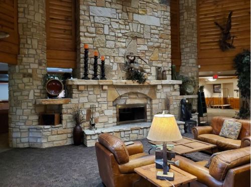 Cozy lobby with a stone fireplace, leather seating, and rustic decor, creating a warm and inviting atmosphere.