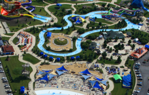 Aerial view of a water park featuring slides, a lazy river, and sunbathing areas with colorful umbrellas and loungers.