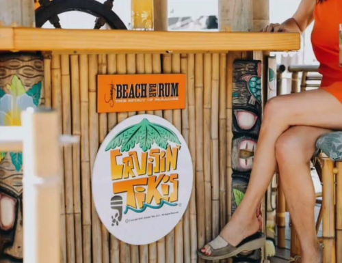 A close-up of a tiki bar with a sign for "Cruisin' Tiki" and a woman’s leg in sandals resting on a bar stool.