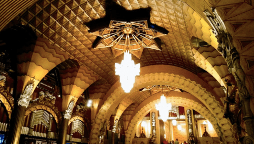 Interior of a grand hall featuring ornate arches, intricate ceiling designs, and elegant chandeliers.