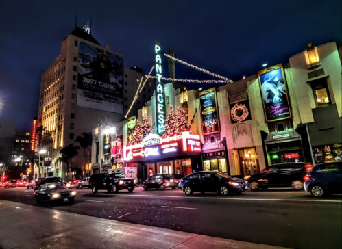 The Pantages Theatre illuminated at night, adorned with festive lights and surrounded by bustling traffic.