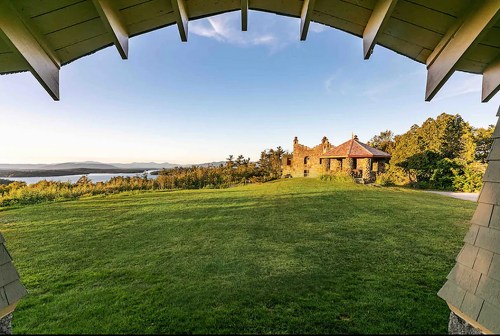 View of a grassy landscape with a distant lake and mountains, framed by an archway of a building.