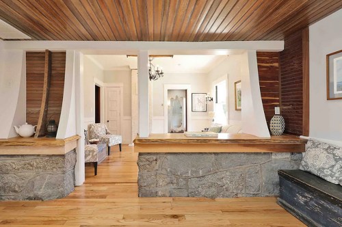 Cozy interior featuring wooden beams, stone accents, and a view into a well-lit living area with stylish furniture.