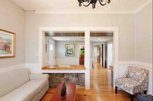 Cozy interior featuring a light gray sofa, a wooden counter, and a patterned chair in a bright, open space.