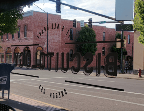 View of a street scene through a restaurant window, featuring the words "Biscuit Co." and a nearby traffic signal.