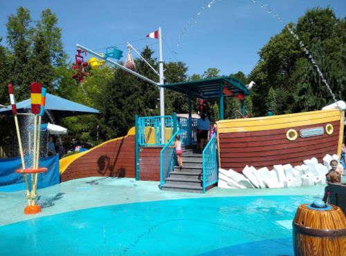 A colorful water play area featuring a large pirate ship structure with slides and water features.