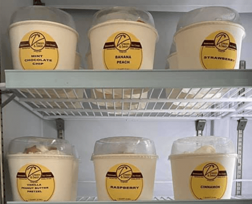 Six tubs of ice cream in a freezer: mint chocolate chip, banana peach, strawberry, vanilla peanut butter pretzel, raspberry, cinnamon.
