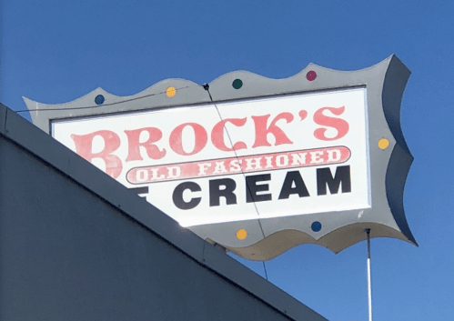Sign for "Brock's Old Fashioned Cream" against a clear blue sky.