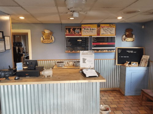 A cozy restaurant counter with a menu board, cash register, and decorative elements in a welcoming atmosphere.