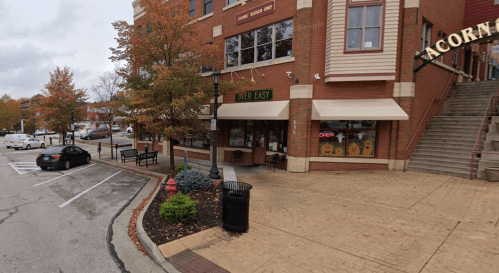 A street view of a restaurant called "Over Easy" with outdoor seating and nearby trees in autumn colors.
