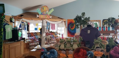A colorful gift shop interior featuring plush frogs, snacks, and vibrant merchandise displays.