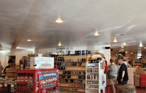 A colorful shop interior with shelves of merchandise, including t-shirts and mugs, and customers browsing.