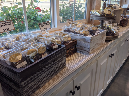A display of packaged treats, including chocolate-dipped Oreos, arranged on a counter by a window.