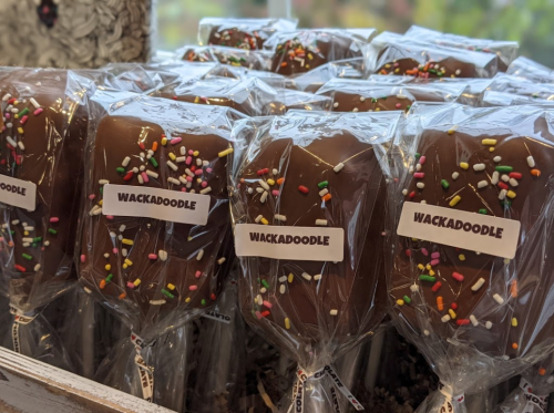 Chocolate-covered treats on sticks, wrapped in clear plastic with colorful sprinkles and labeled "Wackadoodle."