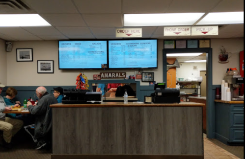 A cozy restaurant interior with a counter, menu boards, and customers dining at tables.