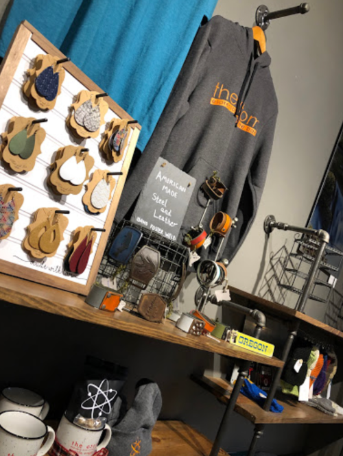 A display of handmade items, including a hoodie, keychains, and wooden ornaments, on wooden shelves.