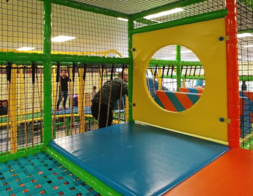 Colorful indoor play area with climbing structures, nets, and soft mats for children to enjoy.