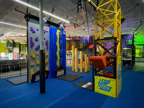 Indoor adventure park featuring climbing walls, a "Leap of Faith" structure, and colorful obstacle courses.