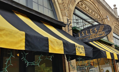 A storefront with black and yellow striped awnings and a sign reading "ISLES BAKERY & COFFEE."