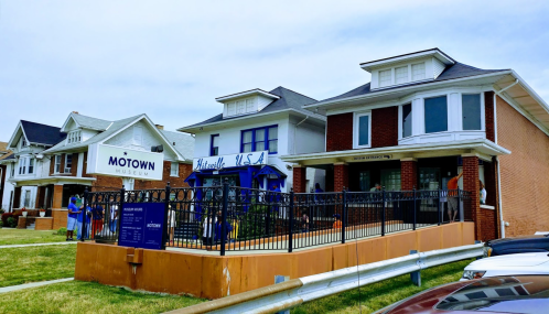 Exterior view of the Motown Museum, featuring a sign and nearby buildings, with a grassy area in front.