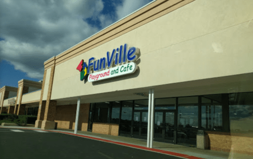 Exterior of FunVille Playground and Cafe, featuring a colorful sign against a clear blue sky.