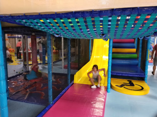 A colorful indoor play area with slides, climbing structures, and children playing in a safe, enclosed environment.