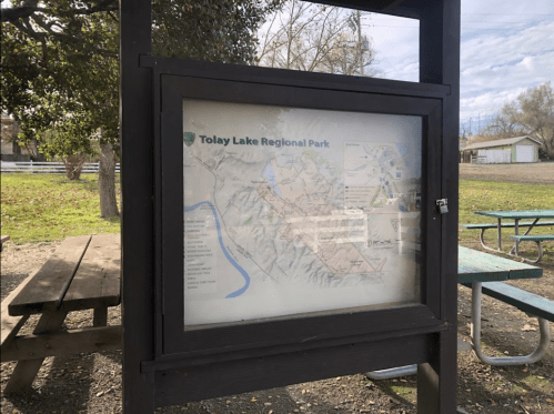 Map display of Tolay Lake Regional Park, featuring trails and park information, with picnic tables in the foreground.