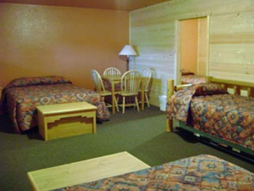 Cozy hotel room with two beds, a wooden table and chairs, and warm-colored walls.