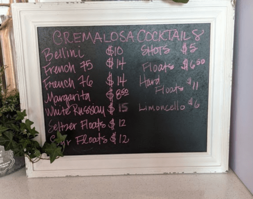 Chalkboard menu listing cocktails and prices, including Bellini, French 75, Margarita, and various floats.