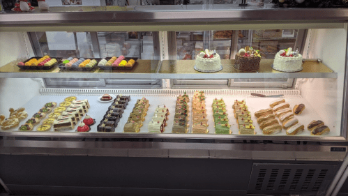 A display case filled with various desserts, including cakes, pastries, and colorful macarons.