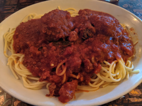 A plate of spaghetti topped with meatballs and marinara sauce.
