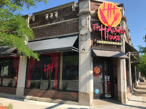 Exterior of The Haunted House restaurant, featuring a bold logo and red accents on a brick building.