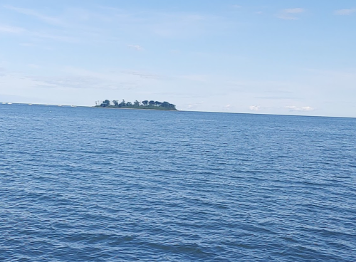 A small island surrounded by calm blue water under a clear sky.
