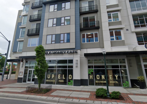 Exterior of a modern building featuring the "Upeo Honey Cafe" with large windows and a sidewalk.