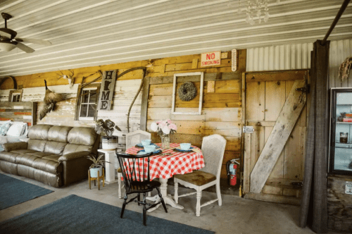 Cozy interior with a checkered tablecloth, a sofa, and rustic decor, featuring a "No Smoking" sign on the wall.